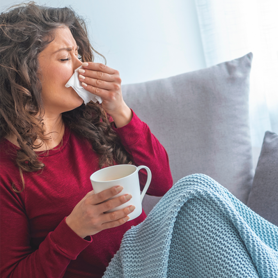 Frau versucht mit Hausmitteln wie Tee und Ruhe die Erkältungssymptome zu lindern.